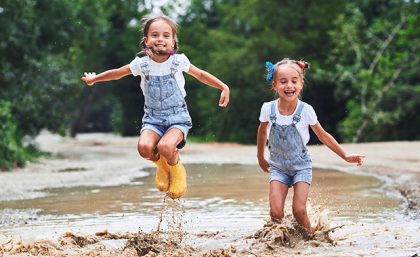 Twin girls jumping in a stream